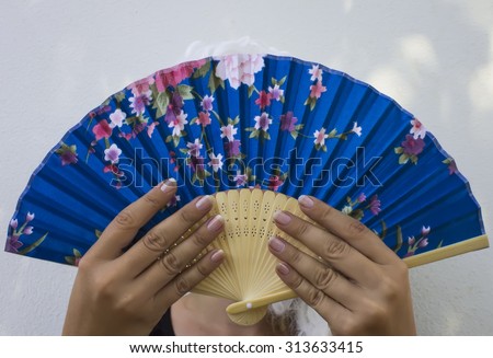 Beautiful girl with a fan in a white wig of the Middle Ages on a white background