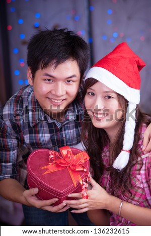young asian girl and boyfriend with a present box at christmas