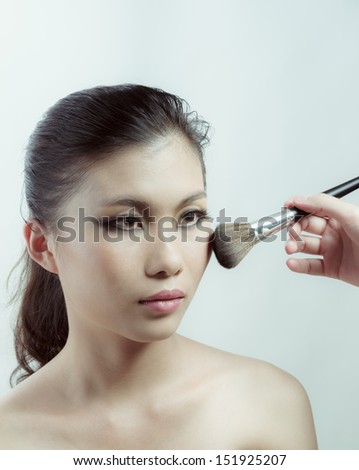 Chinese beauty with professional makeup with brush in photography studio