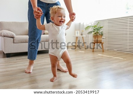 Similar – Image, Stock Photo Toddler learning to walk using push toy; child reaching to play with toy on front of walker