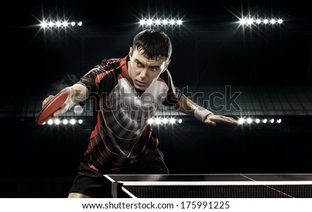 young sports man tennis-player in play on black background with lights