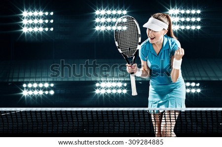 Beautiful girl tennis player with a racket on dark background wiht lights celebrating flawless victory