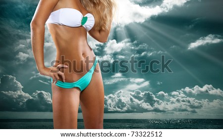 close up shot of young female sexy woman sun bathing in white bikini at sea shore