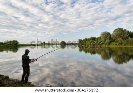 Fishing in river.A fisherman with a fishing rod on the river bank. Man fisherman catches a fish.Fishing, spinning reel, fish, Breg rivers. The concept of a rural getaway. Article about fishing.