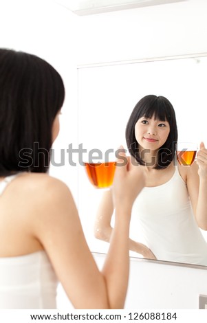 attractive asian woman drinking a tea in the bath room