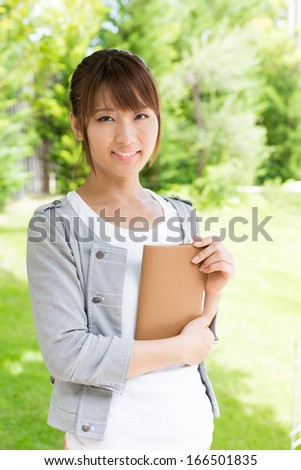 young asian woman holding a book in the park