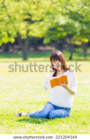 young asian woman reading book in the park
