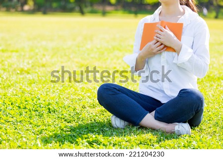 young asian woman reading book in the park