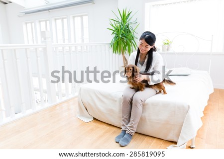 asian woman hugging miniature dachshund on the bed room