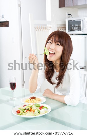attractive asian woman eating lunch in the kitchen
