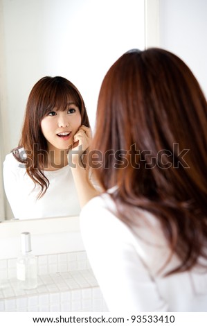 attractive asian woman caring her skin standing front of mirror in the bathroom
