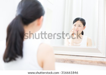 young asian woman looking mirror in the bathroom