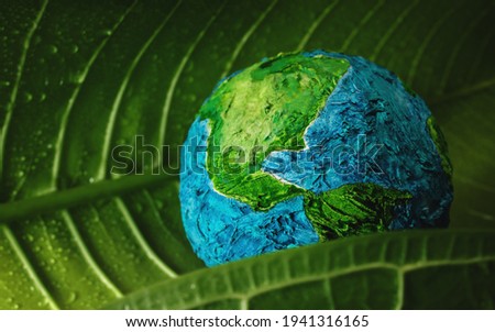 World Earth Day Concept. ESG, Environmental, social and corporate governance. Green Moisture Leaf with Droplet Water Embracing a Handmade Globe. Environment to Love and Care