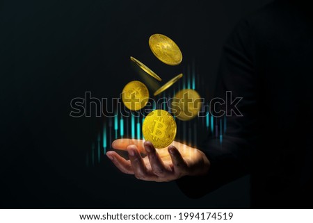 Money Investment on Crypto Currency Coin Concept. Golden Bitcoin Floating over a Trader Hand. Stock Market Graph as background. Dark Scene 商業照片 © 