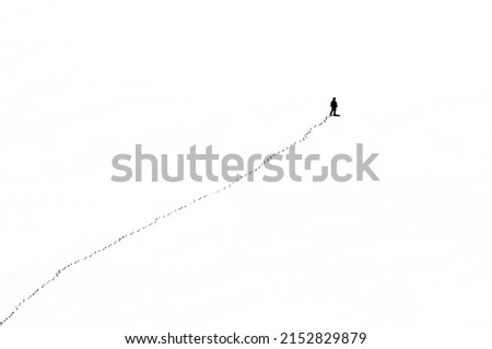 somewhere in mountains (could be anywhere), single person walking forward leaving footprints, clean white in front, symbolic for life as passed days and days to come Foto stock © 