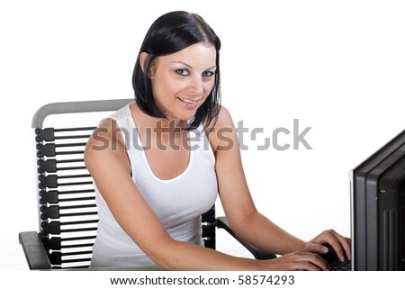 Closeup of a young woman working at a computer. Model is looking toward the camera.