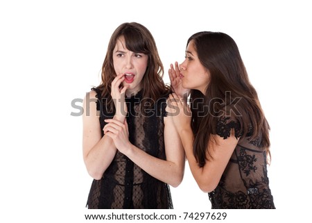 One woman whispering into the ear of another woman who looks shocked.