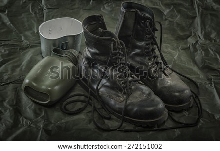 Old combat boots and military canteen on military Canvas  background
