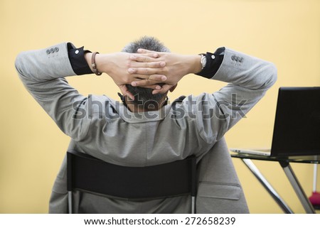 business man relaxing at the laptop with his hands behind his head