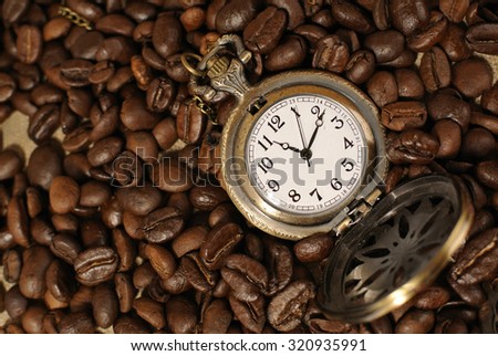 Coffee time: vintage pocket watch with roasted coffee beans on cloth sack