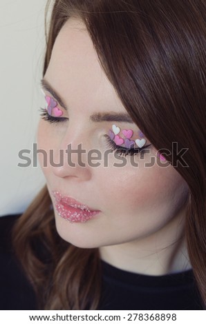 Beautiful woman with colorful candies on her lips, and heart shaped candies on her eyes.