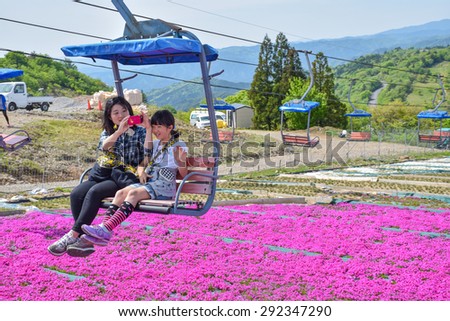 PINK MOSS MOUNTAIN, JAPAN - 17 MAY 2015. Japanese mother and her child take pictures of pink moss flowers, sitting in a cable car on the way up to the top of Pink moss mountain.