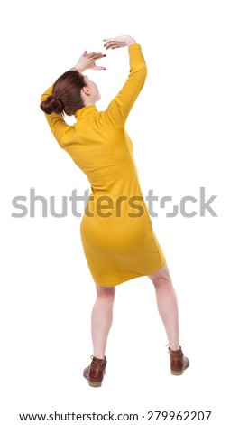 back view woman protects hands from what is falling from above. Rear view people collection. backside view person. Girl in mustard strict dress crouching hands protected from incident from sky