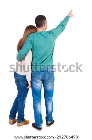 young couple pointing at wal Back view  (woman and man). Rear view people collection.  backside view of person.  I. Man and woman embracing each other to point the finger somewhere in the sky.