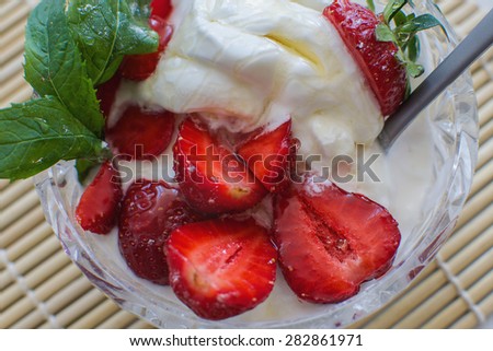 an ice cream with strawberry and honey in the crystal bowl, decorated with mint leaves