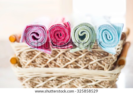 Bath towels of different colors in wicker basket on light background. Stack of colorful dish towels isolated on white. Multi-colored linen napkins for restaurant. Flat mock up for design. Top view