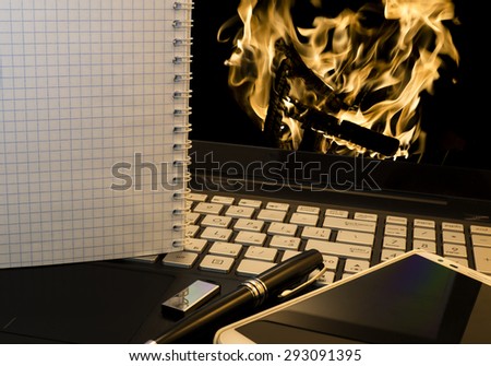 Office workplace with notebook, smart phone, pen, flash drive and wordpad with burning fire background
