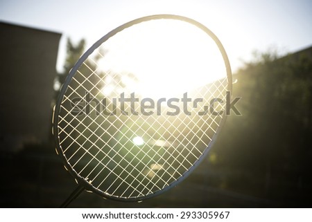 Tennis badminton racket under rays of sun glare bloom filtered background