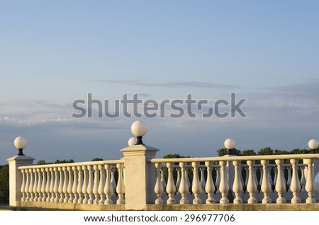Decorative fence of columns on promenade on background of blue sky and clouds