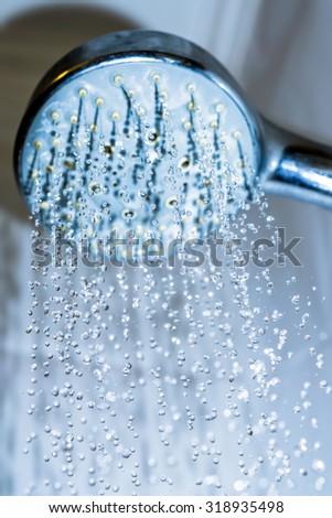 Water drops close-up dripping from the shower blue filtered