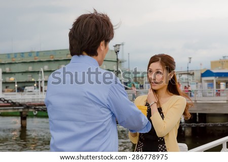 A Japanese man giving a present to a girl friend at a wharf