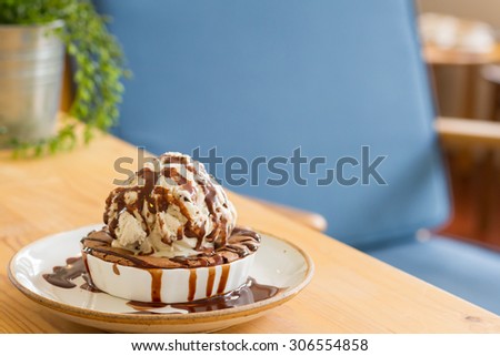 brownie dessert on a white plate with chocolate syrup and vanilla ice cream coffee shop background