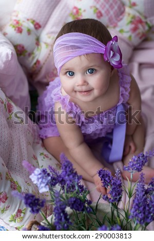 smiling adorable baby girl in lavender dress with flower headband at interior with lavender