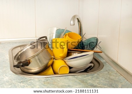 Dirty and unwashed dishes are stacked in the kitchen sink. Unwashed cups, plates, pots, forks and spoons.A mountain of untidy and used dishes. Foto stock © 