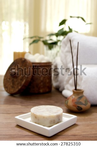 Bar of soap in soap dish with fluffy towels, incense, and soft cotton balls