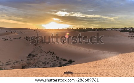 Sunset on the dunes of Mui Ne, Binh Thuan sunset horizon to create sun rays shining down on the sand in which a person walking toward the sun.