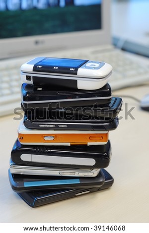 Heap of mobile phones, with computer background. all kinds of brands.