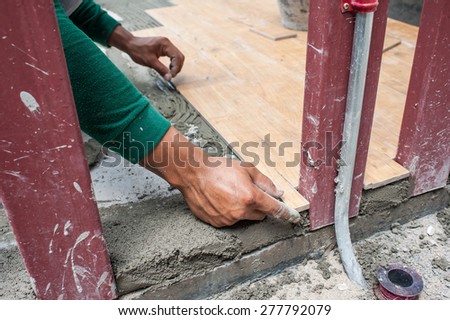 Close-up view of tiler hands fixing tile with spacers at construction  work