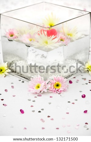 wedding table centre display with a glass square vase with floating flowers