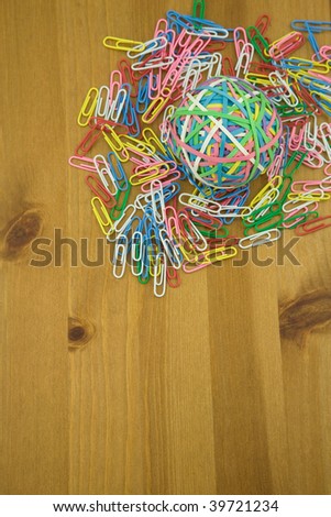 Elevated View of Coloured paper Clips and Rubber band Ball on a wooden table