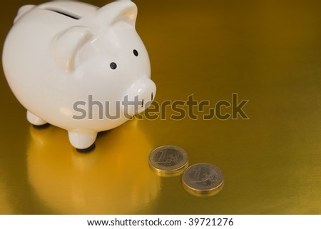 White Piggy bank with British One Pound And One Euro Coins on a Gold Background