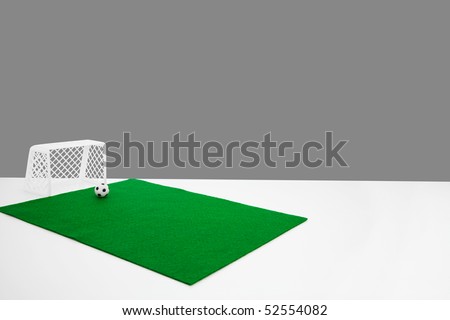 small table top football goal posts. football and green felt fake football pitch on the edge of a white table