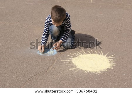 Boy drawing Earth and sun outside