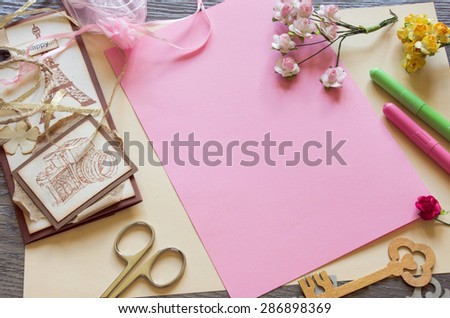 Top view of  paper roses and a pink sheet of paper. Making handmade cards
