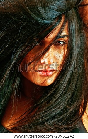 Portrait of the young woman close up. The face is covered with magnificent black hair