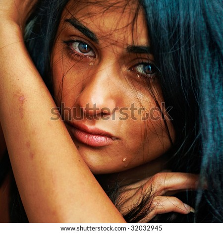 Emotional portrait of the beautiful young suntanned woman with scars on hands and tears on the face